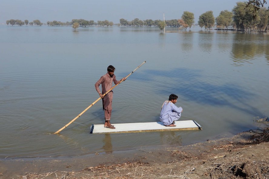Zwei Männer auf einem Floss auf einem überschwemmten Feld in Pakistan 2022.